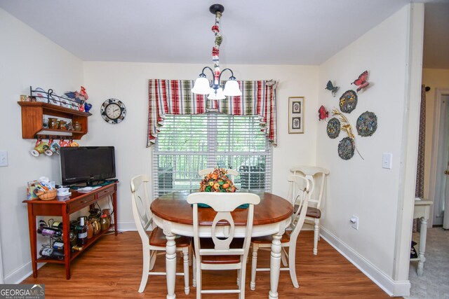 dining room with wood-type flooring and an inviting chandelier