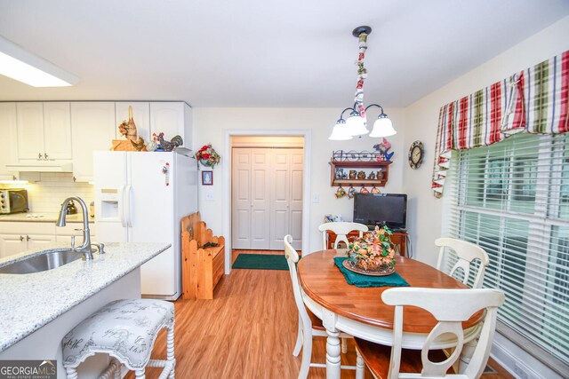 dining space featuring light hardwood / wood-style flooring, sink, and a chandelier