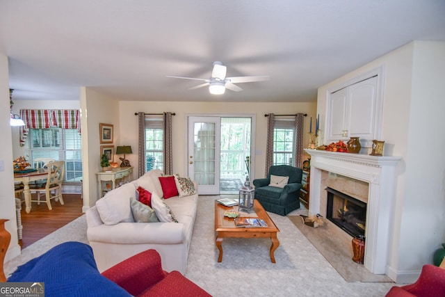 living room featuring a high end fireplace, light wood-type flooring, and ceiling fan