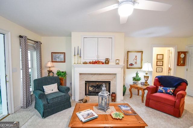 carpeted living room with ceiling fan and a fireplace