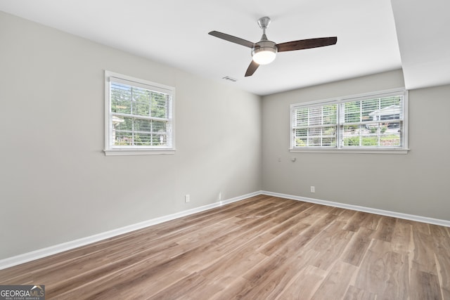 unfurnished room with a wealth of natural light, ceiling fan, and light wood-type flooring