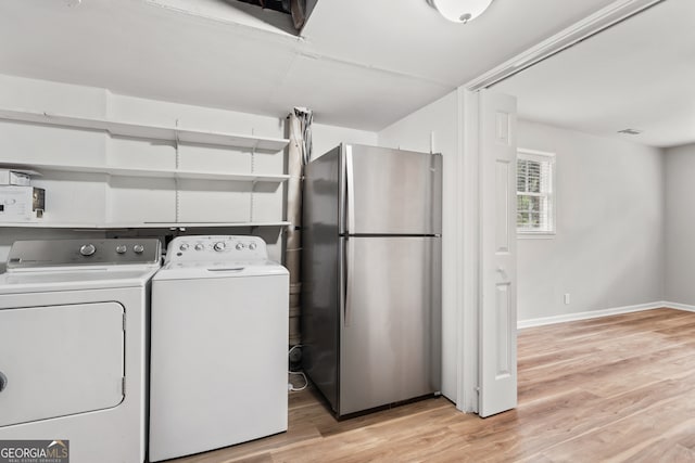 clothes washing area featuring washing machine and clothes dryer and light wood-type flooring