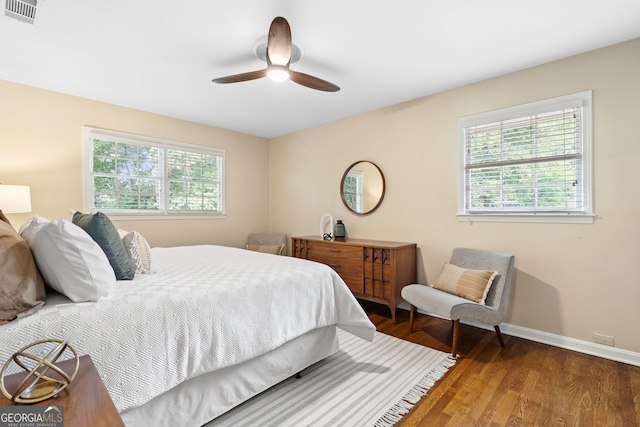 bedroom featuring multiple windows, ceiling fan, and dark hardwood / wood-style flooring