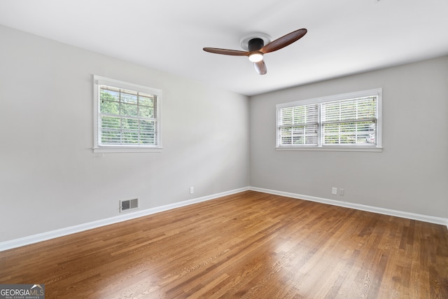 empty room with hardwood / wood-style flooring, plenty of natural light, and ceiling fan