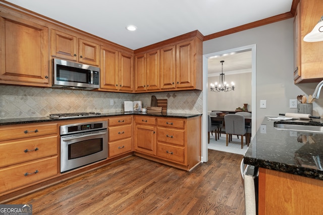 kitchen featuring decorative light fixtures, a notable chandelier, dark wood-type flooring, stainless steel appliances, and sink