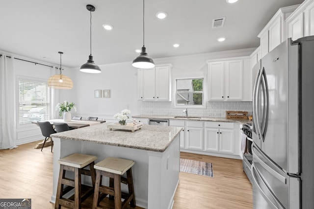 kitchen featuring stainless steel appliances, hanging light fixtures, and white cabinetry