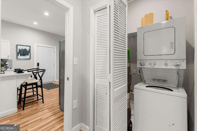 laundry room with light wood-type flooring and stacked washer and dryer