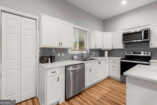 kitchen with stainless steel appliances, sink, light wood-type flooring, and white cabinets