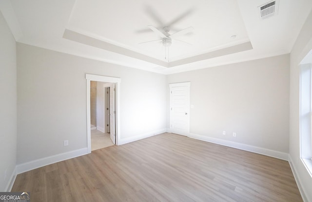 unfurnished room featuring ceiling fan, a raised ceiling, and light hardwood / wood-style flooring