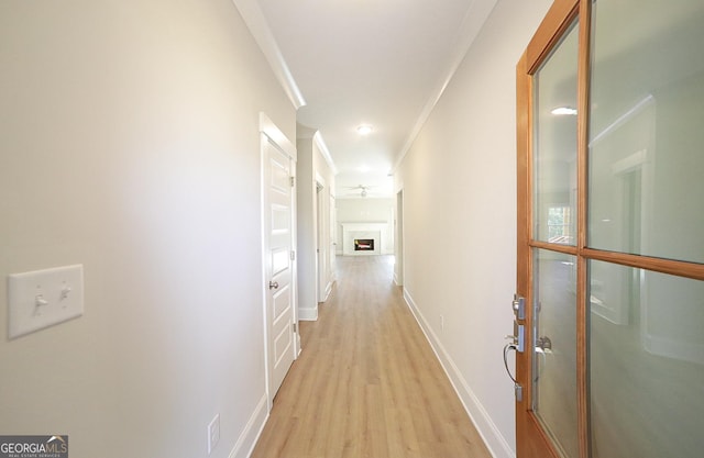 corridor with light hardwood / wood-style flooring and crown molding