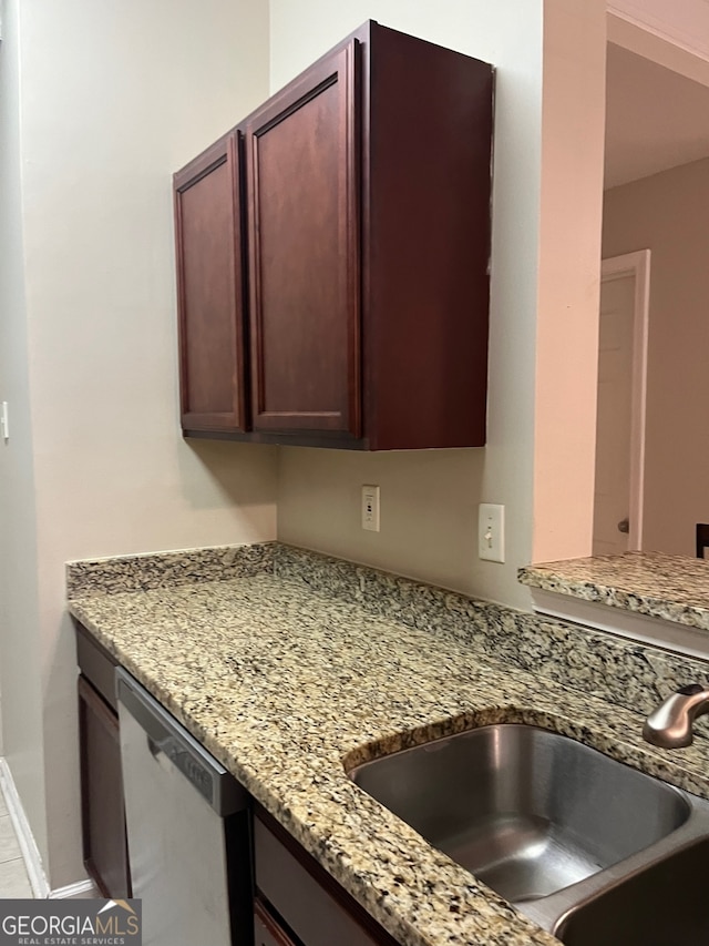 kitchen featuring dishwasher, sink, and light stone countertops