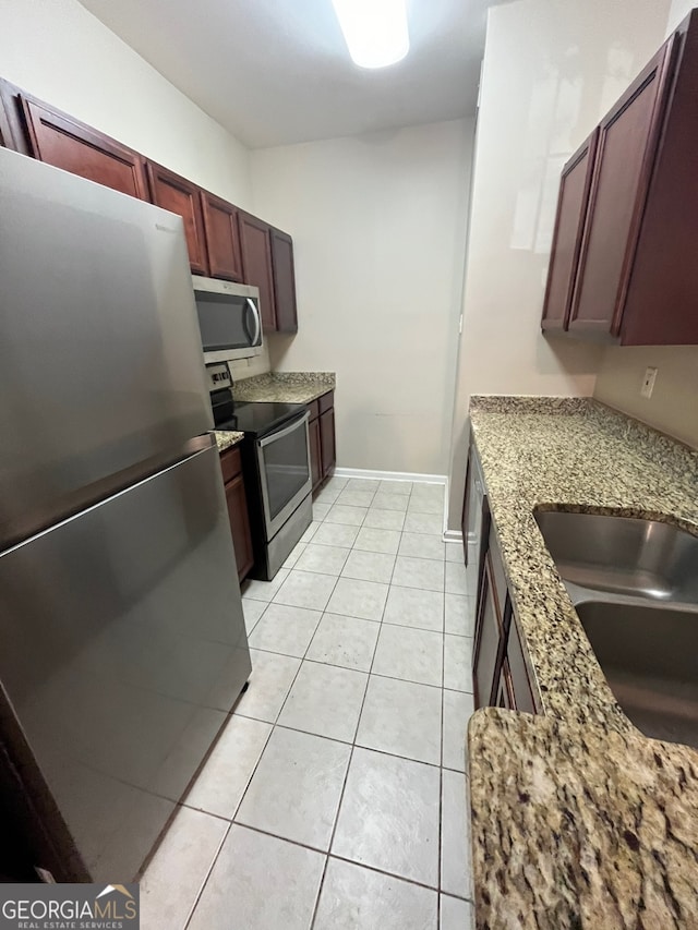 kitchen featuring light stone counters, sink, light tile patterned floors, and appliances with stainless steel finishes