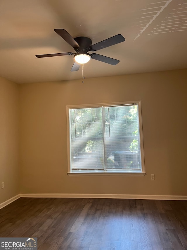 empty room with ceiling fan, a wealth of natural light, and dark hardwood / wood-style flooring