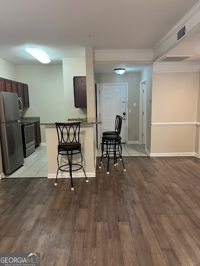 kitchen featuring light hardwood / wood-style flooring, kitchen peninsula, stainless steel appliances, and a kitchen breakfast bar