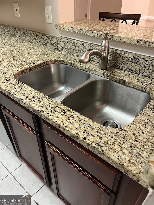 room details with light tile patterned floors, light stone counters, dark brown cabinetry, and sink