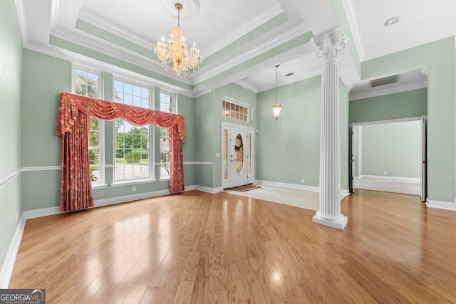 foyer with light hardwood / wood-style flooring, decorative columns, an inviting chandelier, and crown molding