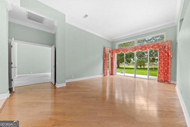 empty room featuring light hardwood / wood-style flooring, ornamental molding, and lofted ceiling