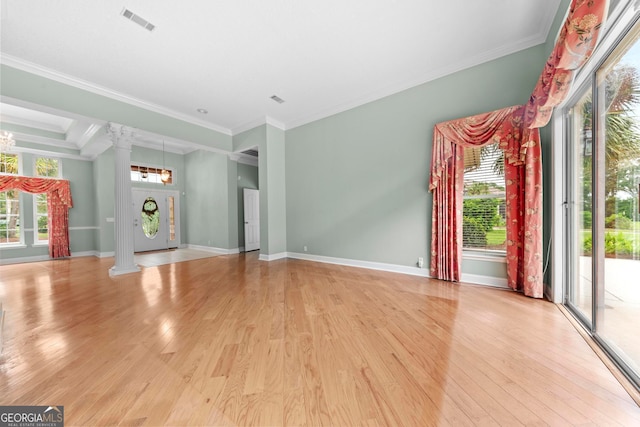 unfurnished living room featuring light wood-type flooring, ornamental molding, and ornate columns