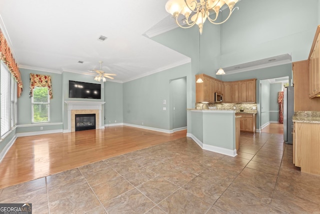 kitchen with appliances with stainless steel finishes, decorative backsplash, ceiling fan with notable chandelier, crown molding, and light hardwood / wood-style flooring