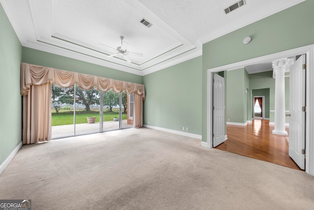 unfurnished room with ceiling fan, a raised ceiling, a textured ceiling, carpet, and ornate columns