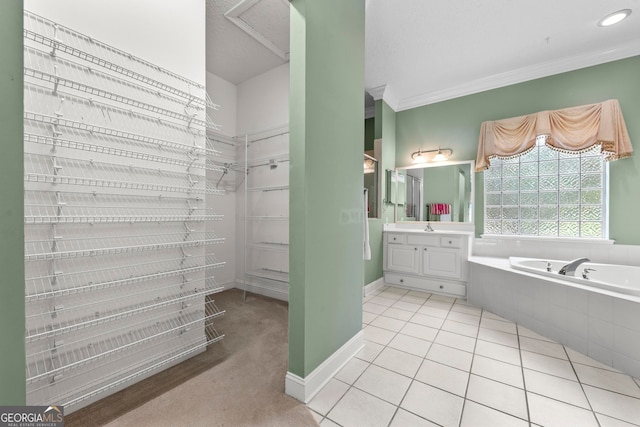 bathroom featuring tiled tub, vanity, ornamental molding, and tile patterned floors