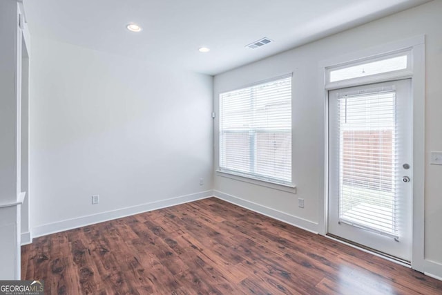 unfurnished room featuring a healthy amount of sunlight and dark hardwood / wood-style flooring