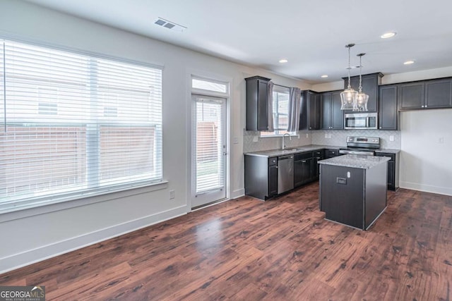 kitchen featuring a kitchen island, decorative light fixtures, appliances with stainless steel finishes, and dark wood-type flooring