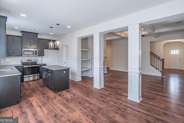 kitchen with light stone counters, stainless steel appliances, beamed ceiling, dark wood-type flooring, and a kitchen island