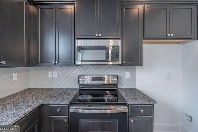 kitchen with backsplash, light stone counters, appliances with stainless steel finishes, and dark brown cabinets