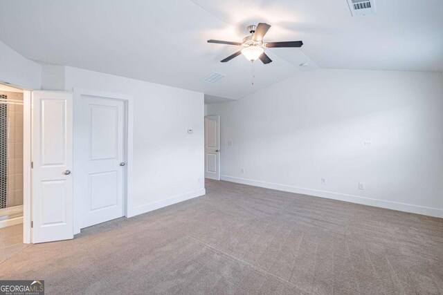 interior space with lofted ceiling, light colored carpet, ensuite bath, and ceiling fan