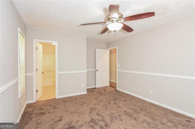 unfurnished bedroom with a textured ceiling, carpet flooring, connected bathroom, and ceiling fan