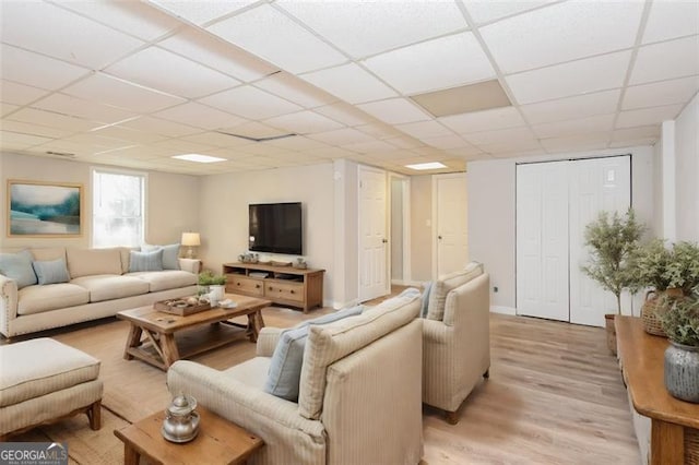 living room featuring light wood-type flooring and a drop ceiling