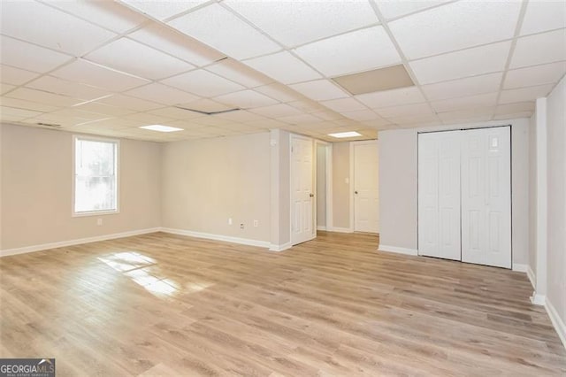 basement featuring light wood-type flooring and a paneled ceiling