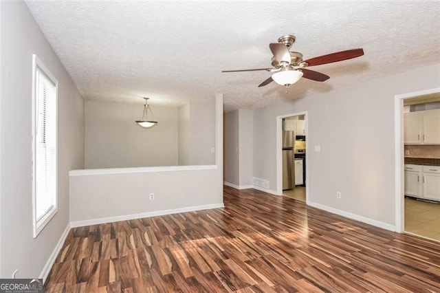 empty room featuring dark wood-type flooring, a textured ceiling, and ceiling fan