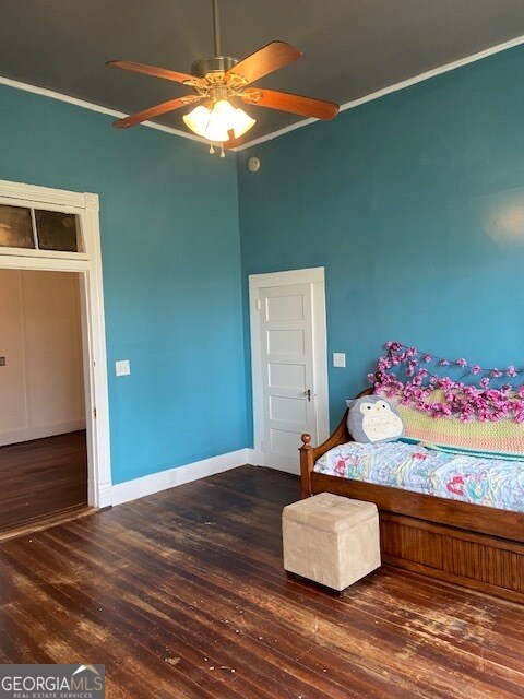 bedroom featuring ornamental molding, dark wood-type flooring, and ceiling fan