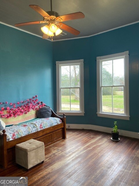 bedroom with crown molding, multiple windows, hardwood / wood-style flooring, and ceiling fan