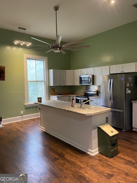 kitchen with dark hardwood / wood-style flooring, appliances with stainless steel finishes, an island with sink, and white cabinetry