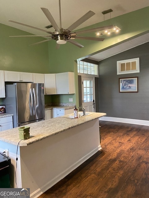 kitchen featuring white cabinets, stainless steel fridge, and vaulted ceiling