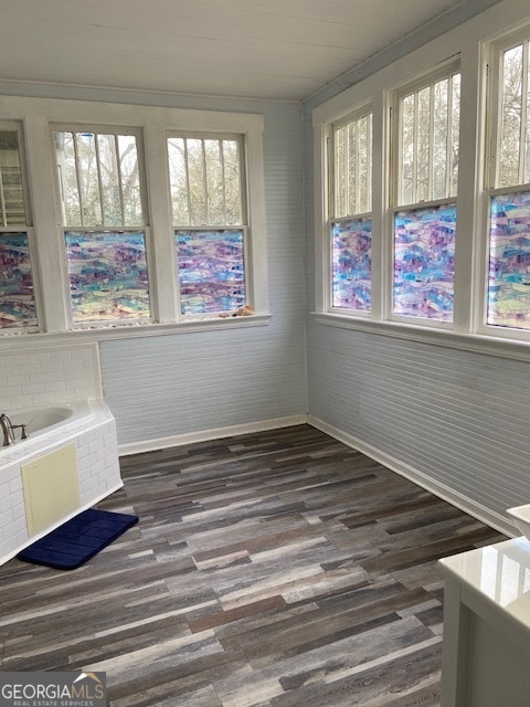 bathroom featuring ornamental molding, wood-type flooring, and a tub