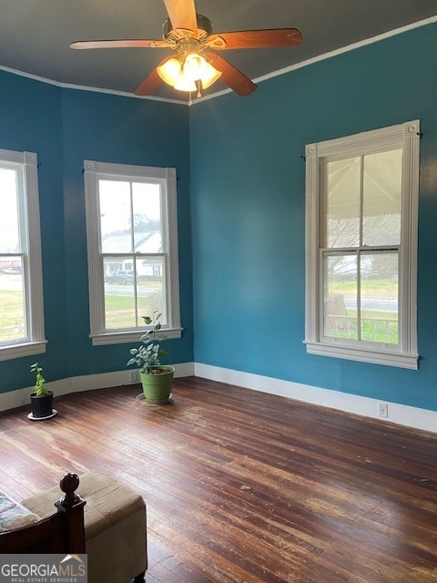 empty room with crown molding, plenty of natural light, ceiling fan, and hardwood / wood-style floors