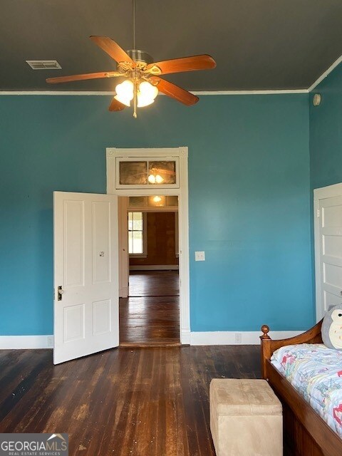 unfurnished bedroom featuring ceiling fan, ornamental molding, and dark hardwood / wood-style flooring