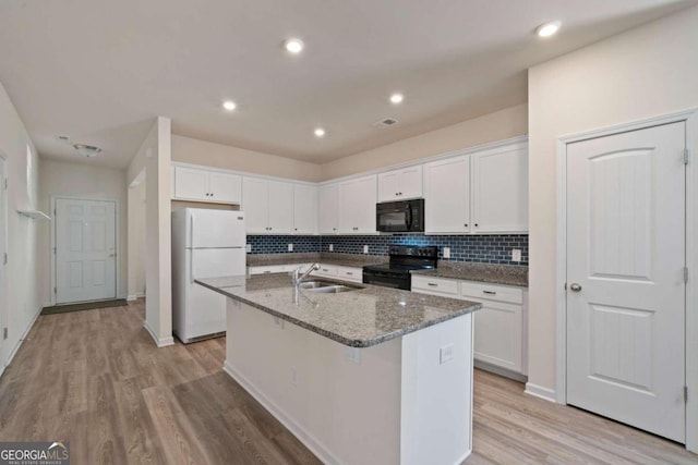 kitchen featuring a kitchen island with sink, dark stone counters, black appliances, white cabinets, and sink