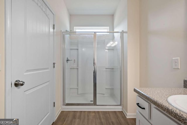 bathroom featuring hardwood / wood-style floors, vanity, and a shower with door