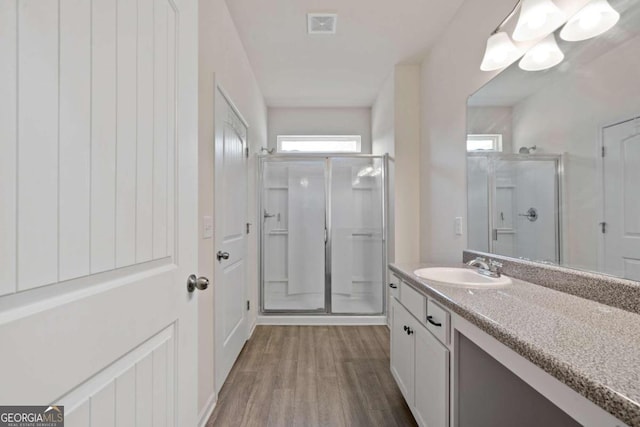 bathroom featuring wood-type flooring, vanity, and a shower with shower door