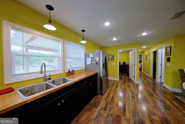 kitchen with stainless steel fridge, a wealth of natural light, decorative light fixtures, sink, and dark wood-type flooring