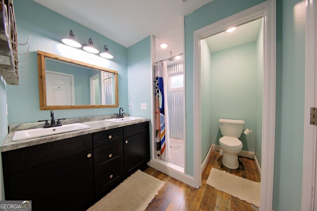 bathroom with a shower with shower curtain, wood-type flooring, toilet, and vanity