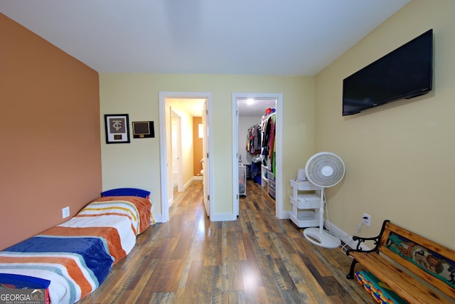 bedroom featuring dark wood-type flooring, a walk in closet, and a closet