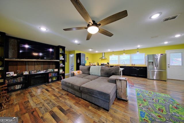 living room featuring wood-type flooring, sink, and ceiling fan