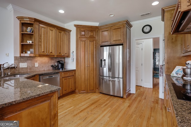 kitchen featuring dark stone countertops, light hardwood / wood-style flooring, stainless steel appliances, and sink