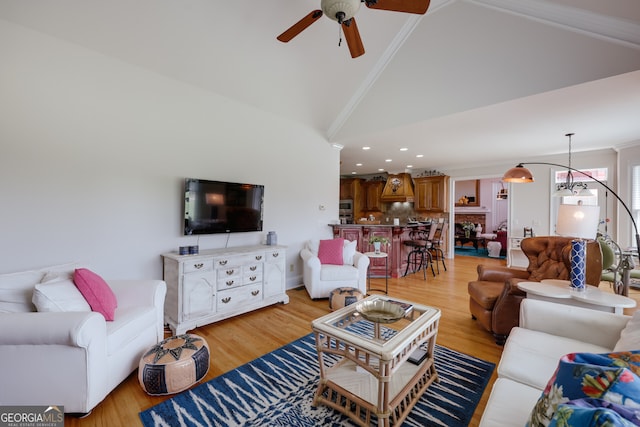 living room with crown molding, light hardwood / wood-style flooring, ceiling fan, and high vaulted ceiling